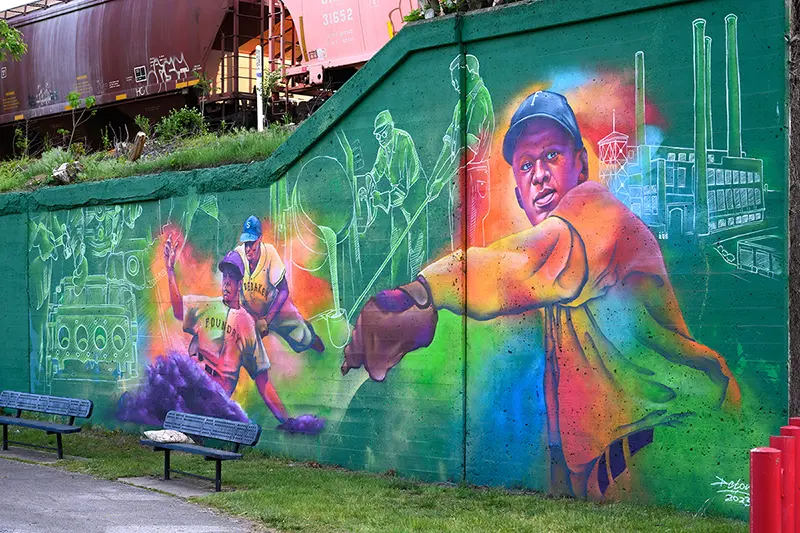 A colorful mural depicting baseball players and factory workers