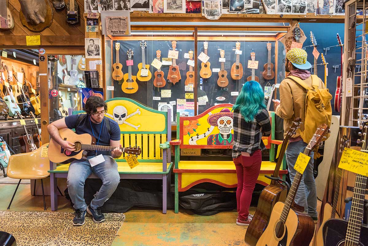 Student journalist Carlos De Loera plays a guitar at Rockin' Robin Guitars & Music store in Houston, Texas.