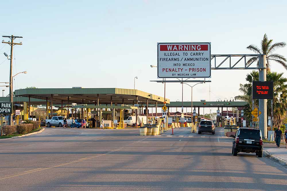 The U.S.-Mexican border with a road sign that says &ldquo; WARNING: Illegal to carry firearms/ammunition into Mexico. Penalty - prison by Mexican Law.&rdquo;