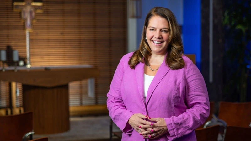 Catholic Charities USA building exterior with purple banners, seen through spring foliage.