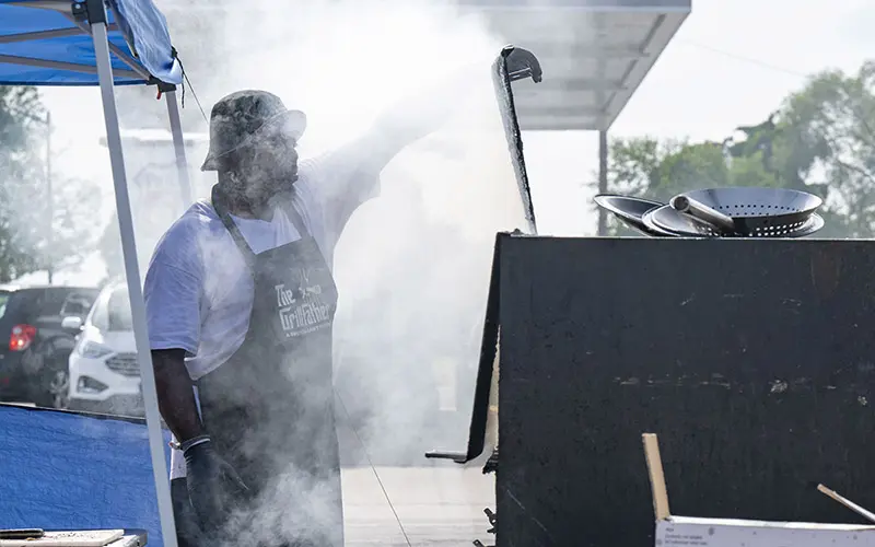 Entrepreneur Raymond Barbour stands in front of his port-a-pit grill while smoke envelopes his face.