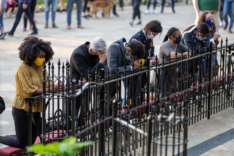 People wearing masks kneel to pray at the Grotto.