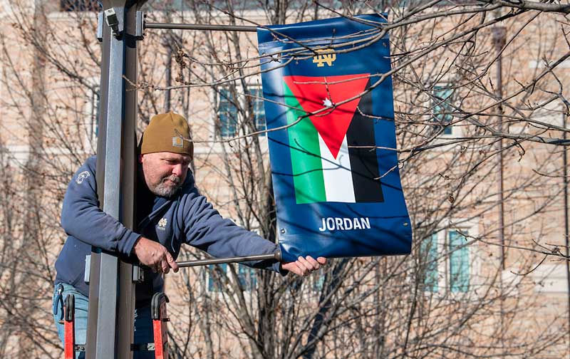 A man installs a banner representing Jordan&rsquo;s flag on a lamp post.