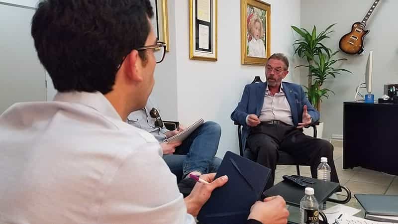 A man is interviewed by two students.