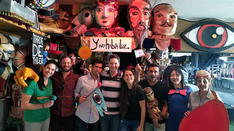A group of students standing in front of colorful artwork pose for a photo.