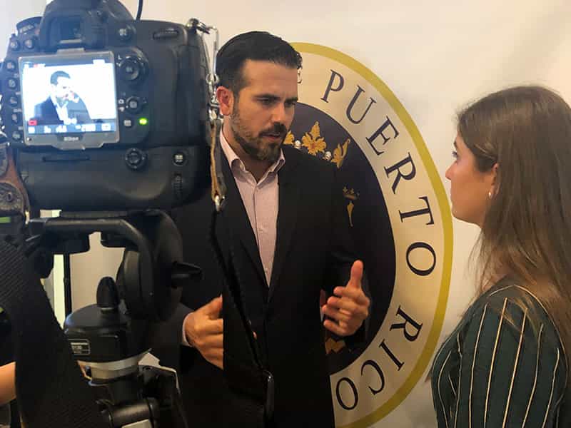 A student stands next to governor of Puerto Rico, Ricardo Rosselló, and interviews him.