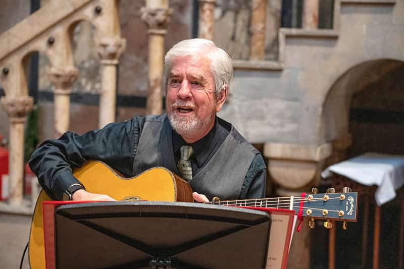 A man sings and plays an acoustic guitar.
