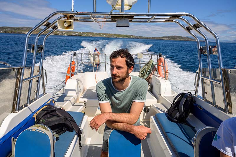 A man rides a boat on a sunny day.