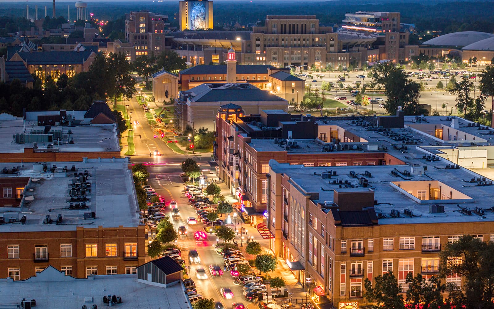 Eddy Street at dusk, shot from above with the Hesburgh Library and the Word of Life Mural&mdash;more commonly known as Touchdown Jesus&mdash;lit up in the background.