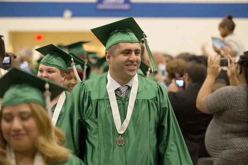 Rizan Hajji Mohamed stands in his green graduation robes.