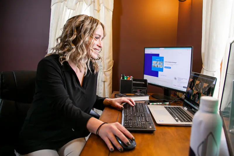 Katie Reigelsperger sits at her computer wearing professional clothes.