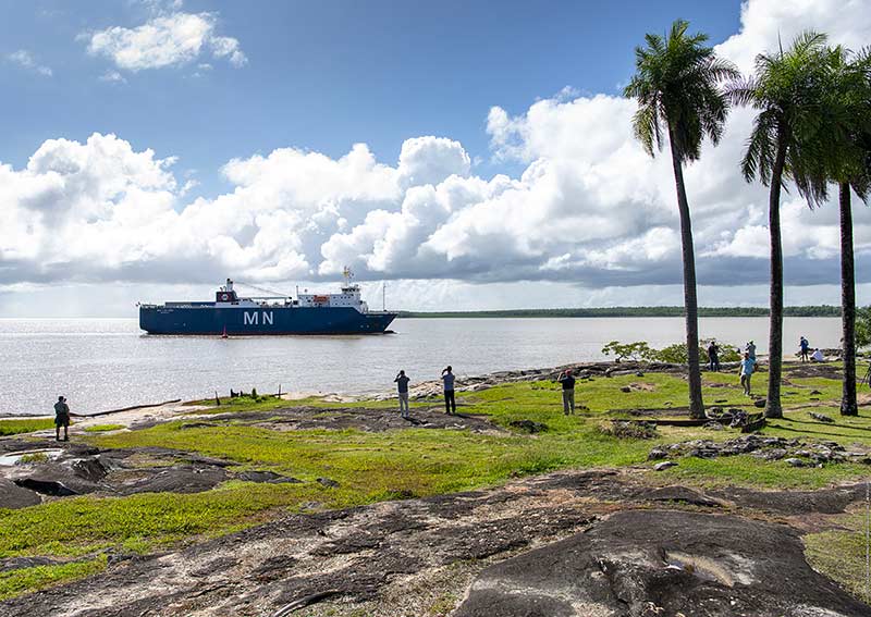 A ship, carrying NASA&rsquo;s James Webb Space Telescope as cargo, arrives. In the foreground there are several people on land standing by taking photos.