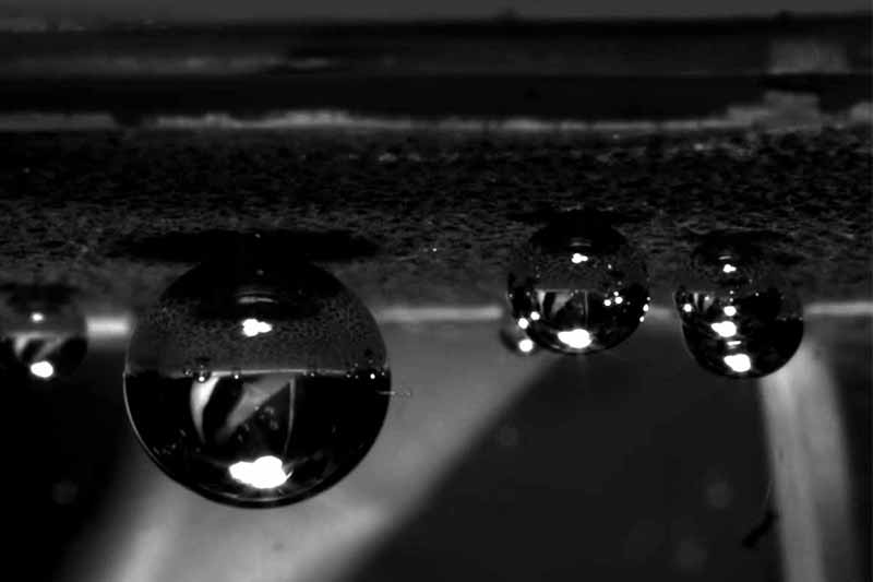 A black and white video screenshot of bubbles forming in space.