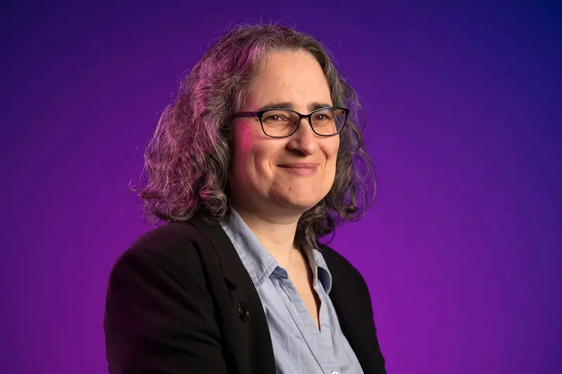 A headshot of Marya Lieberman against a bright purple background.