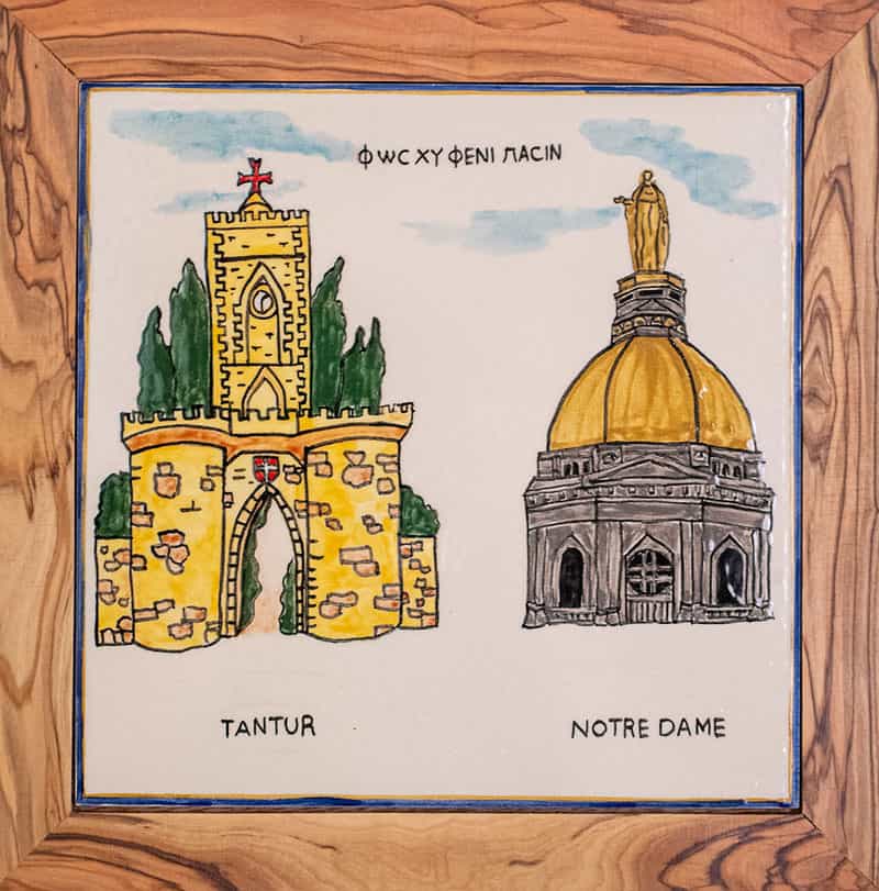 A colorful painting, framed, of Tantur entrance and Notre Dame's Golden Dome.