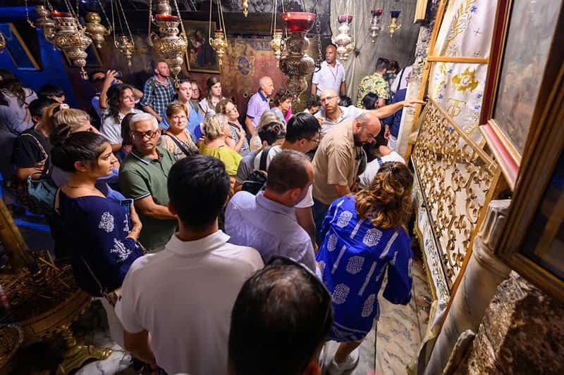 A group of people stand and wait to enter the shrine over the birthplace of Jesus.
