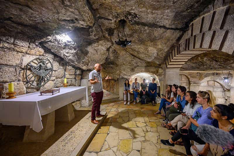 A tour guide talks to students sitting in the caves underneath the Church of the Nativity in Bethlehem.