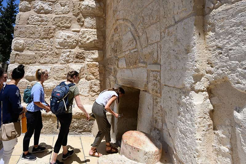 Students lean over in order to enter the small opening of the Church of the Nativity in Bethlehem.