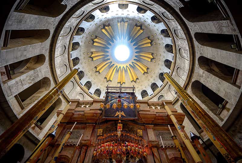 Students tour the Holy Sepulchre, one student stands next to brightly lit candles.
