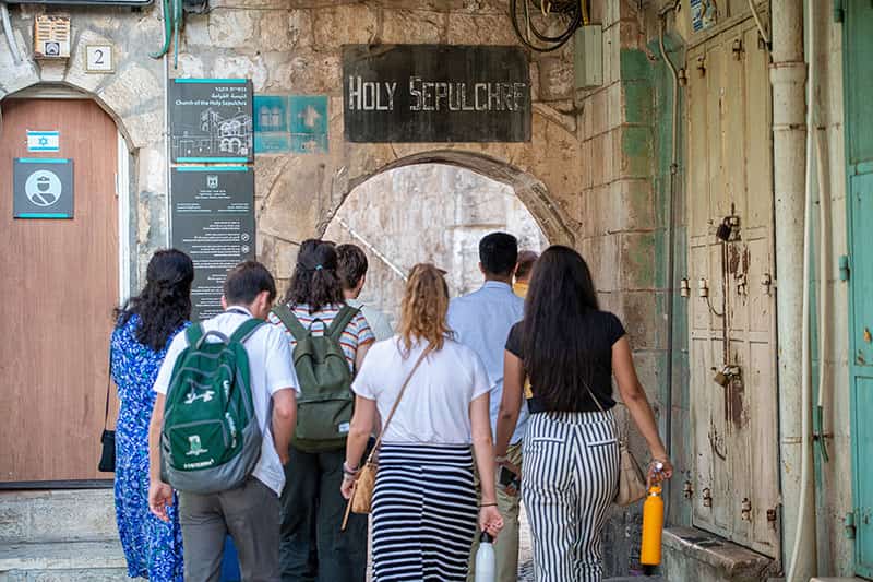 Students back facing the camera, walk away toward an entrance.