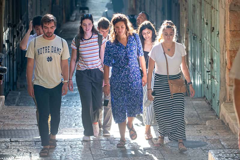 On a bright, sunny day, students walk down stairs heading toward the Western Wall.