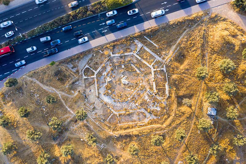 A birds eye view shot of Ruins of the Church of the Seat of Mary next to a busy highway.