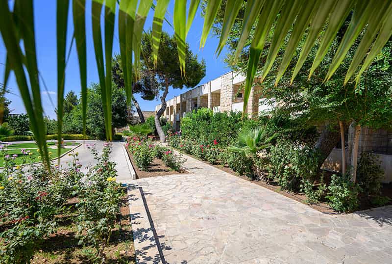 A pathway around a building, flower beds between each walk way and green trees in the foreground.