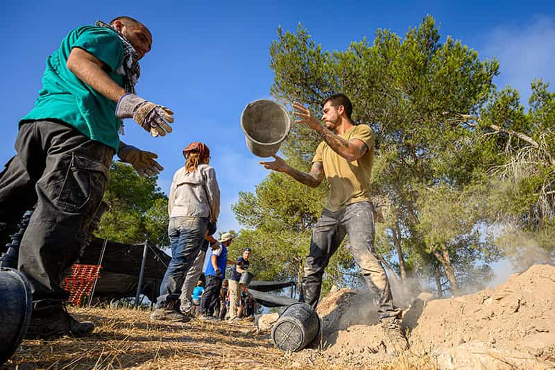 A bucket floats in the air as one person tosses a bucket to another.