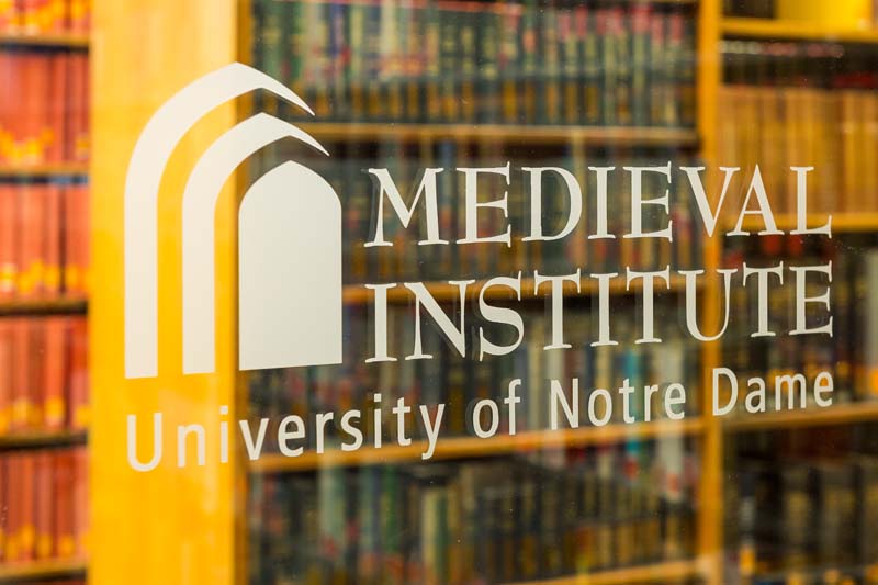The Medieval Institute logo etched on glass on a door in the library.