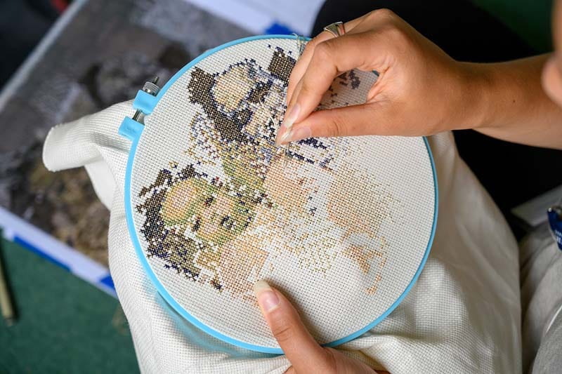 A close up of her embroidery project, two faces appearing.