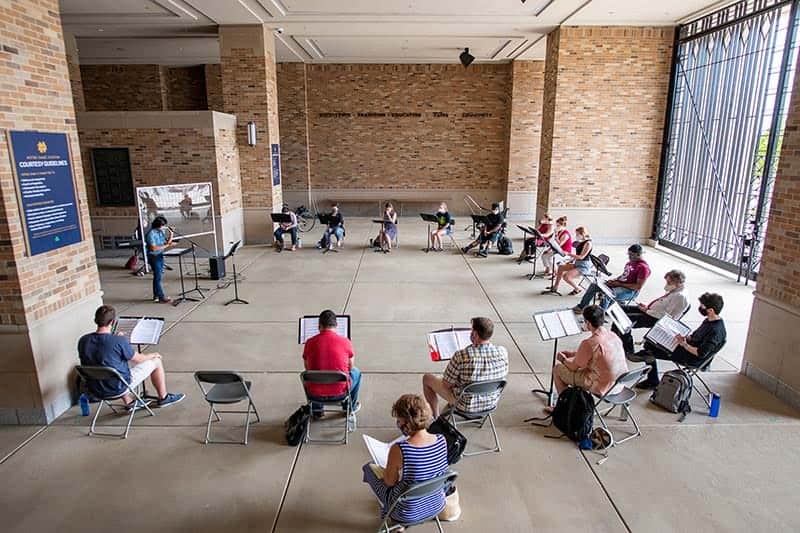 A large choir of 16 people gather, 6ft apart and masked, as they rehearse in the football stadium&rsquo;s Leahy Gate.