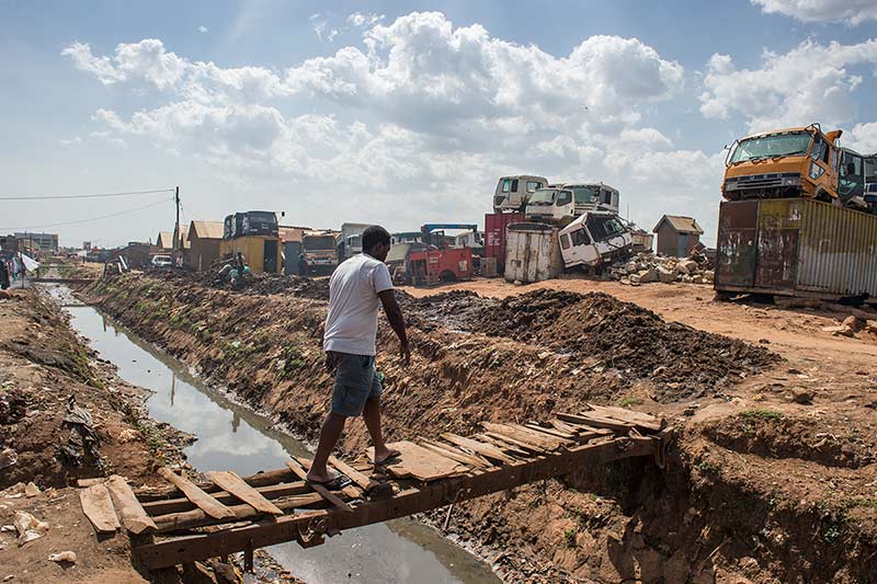 YALI fellow Alex Kawooya crosses a foot bridge in Kalerowa slum where he lived for 11 years.
