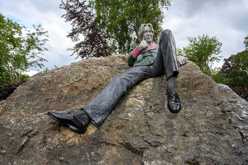 A statue of a man leaning on top of a large rock.