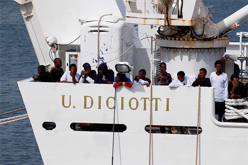 People stand on a ship looking out at sea.