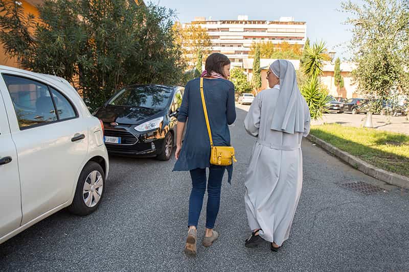 Two people talk as they walk down a road.