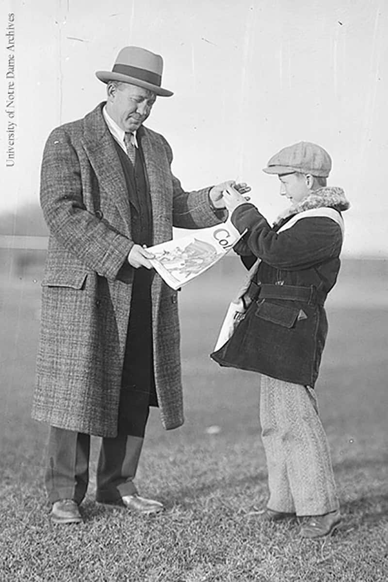 Knute Rockne buys a magazine from a boy.