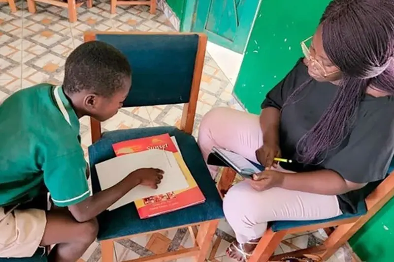 A young man and a woman are studying with their papers on the chair between them.