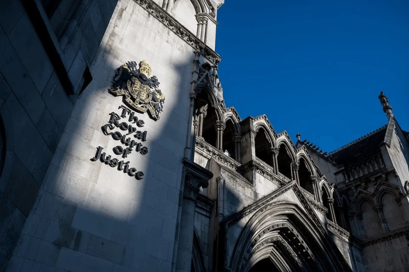 The Royal Courts of Justice building with its prominent sign, ornate architecture, and a blue sky in the background.