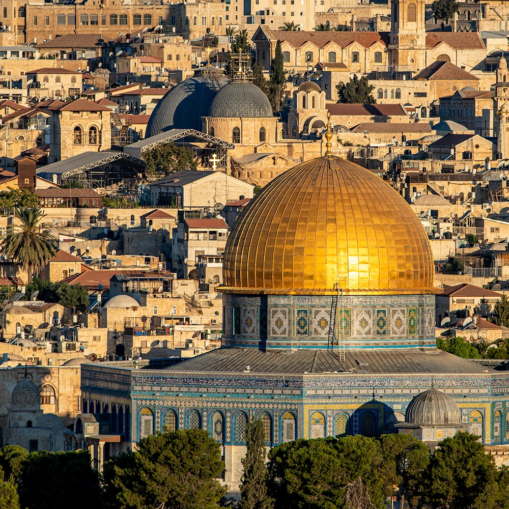 A sunny, close-up view of the golden Dome of the Rock and the Al-Aqsa Mosque compound, with the Jerusalem cityscape in the background.