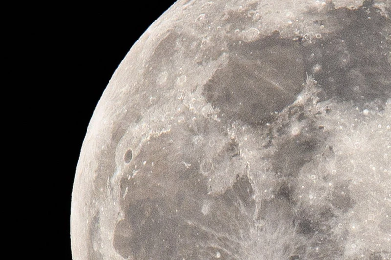 A close-up view of the moon's cratered surface against the blackness of space.